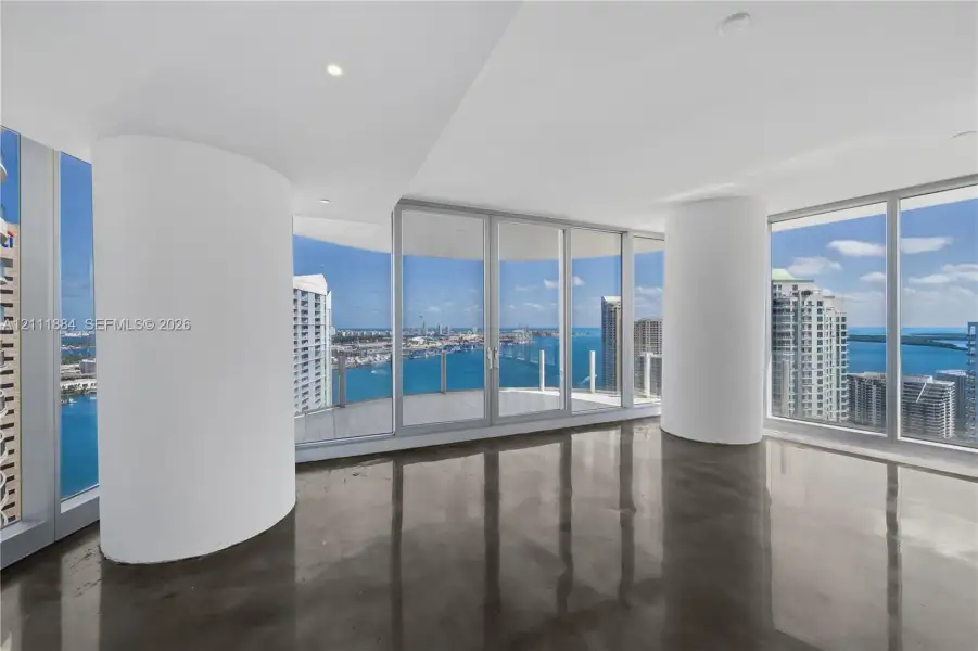 Floor-to-ceiling glass walls, polished concrete flooring, rounded structural columns, recessed lighting, and integrated balcony access Floor-to-ceiling glass walls, polished concrete flooring, rounded structural columns, recessed lighting, and integrated balcony access
