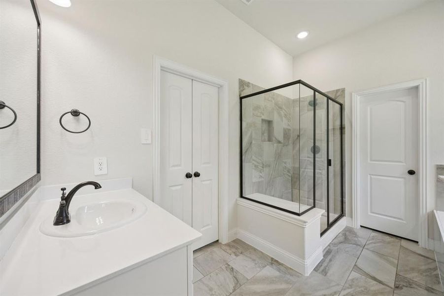 En-suite bathroom with marble like tiles, a separate shower, garden tub, separate vanities, and large walk-in closet.