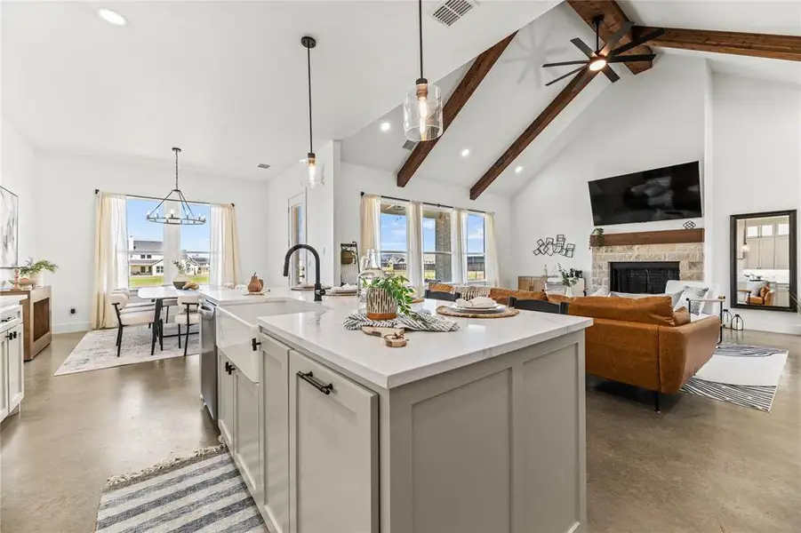 Kitchen featuring concrete flooring, beam ceiling, a stone fireplace, recessed lighting, and a chandelier Kitchen featuring concrete flooring, beam ceiling, a stone fireplace, recessed lighting, and a chandelier