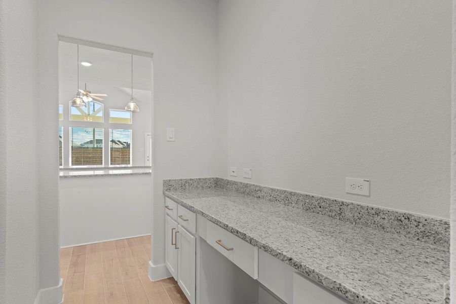 A stunning built-in granite countertop workspace offers endless possibilities — ideal for a coffee bar, serving area, or even a small home command center. This thoughtful CastleRock detail adds both beauty and function to the layout.