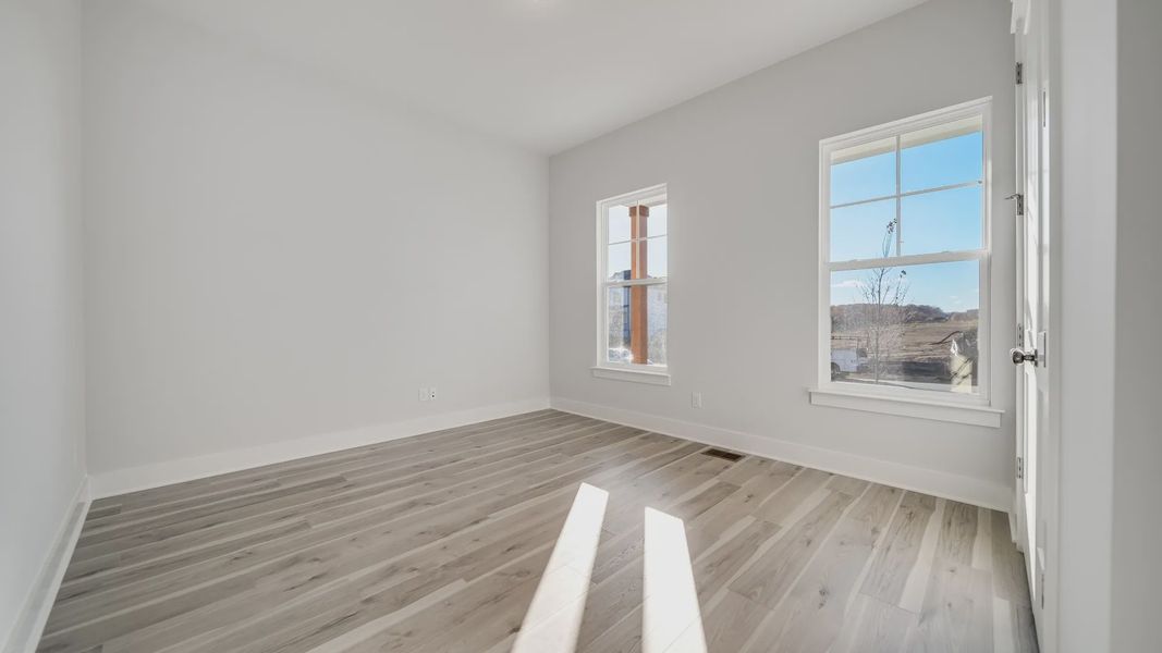 Secondary bedroom with hard-surface flooring and large windows