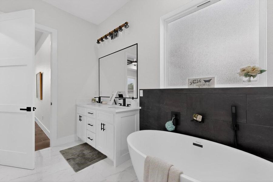 Primary Bathroom featuring a freestanding bath, double vanity, and light marble finish flooring Primary Bathroom featuring a freestanding bath, double vanity, and light marble finish flooring