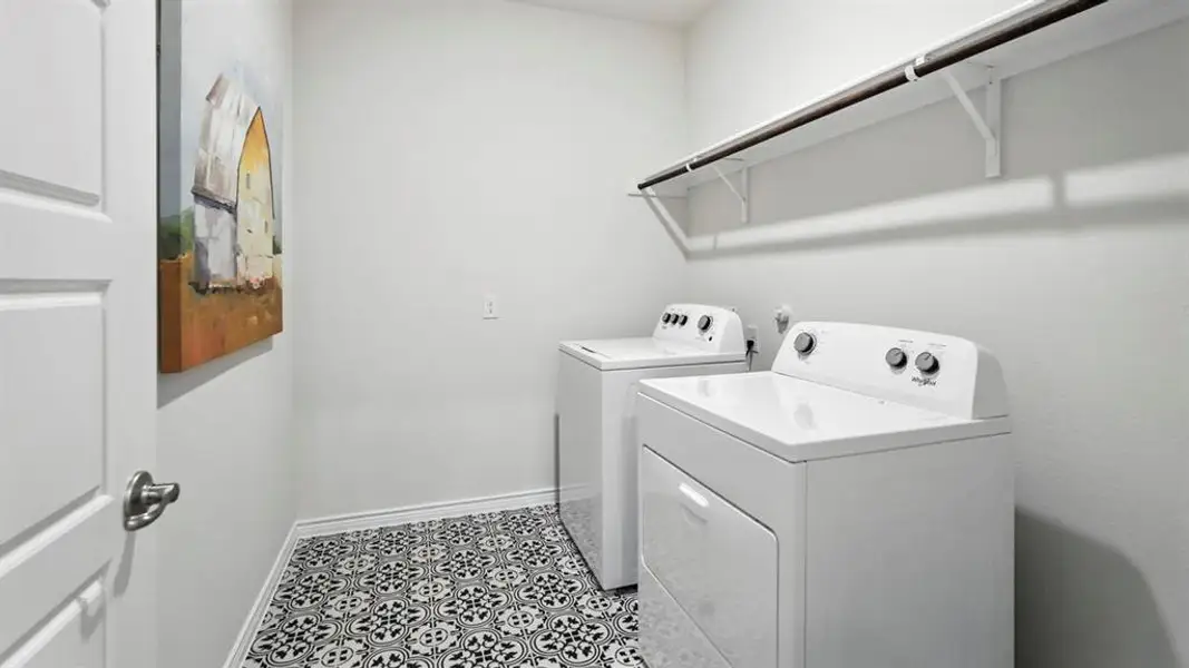 Washroom with washer and clothes dryer and tile patterned flooring Washroom with washer and clothes dryer and tile patterned flooring