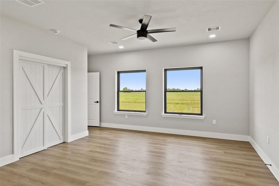 Relaxing primary suite with backyard views and a spa-inspired en suite bath featuring a fully tiled wet room, soaking tub, dual shower heads, double vanities, and a private water closet. The spacious walk-in closet includes built-in drawers for added organization.