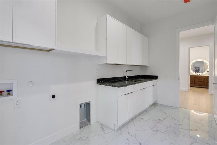 Clothes washing area with electric dryer hookup, marble finish floor, a sink, baseboards, and cabinet space