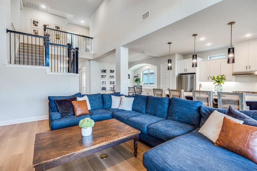 Living area featuring wood finished floors, recessed lighting, a towering ceiling, and arched walkways