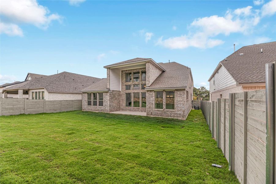 Back of house featuring a fenced backyard, a patio area, brick siding, and roof with shingles