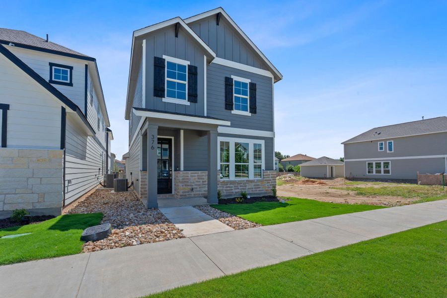 View of front of house featuring board and batten siding, a porch, stone siding, and a front yard View of front of house featuring board and batten siding, a porch, stone siding, and a front yard