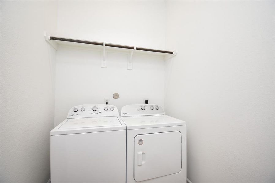 The utility room easily accommodates dual laundry appliances.