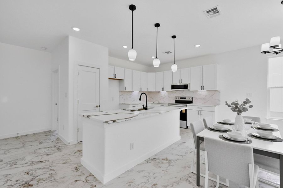 Kitchen featuring stainless steel electric range, white cabinets, light stone counters, hanging light fixtures, and a center island with sink