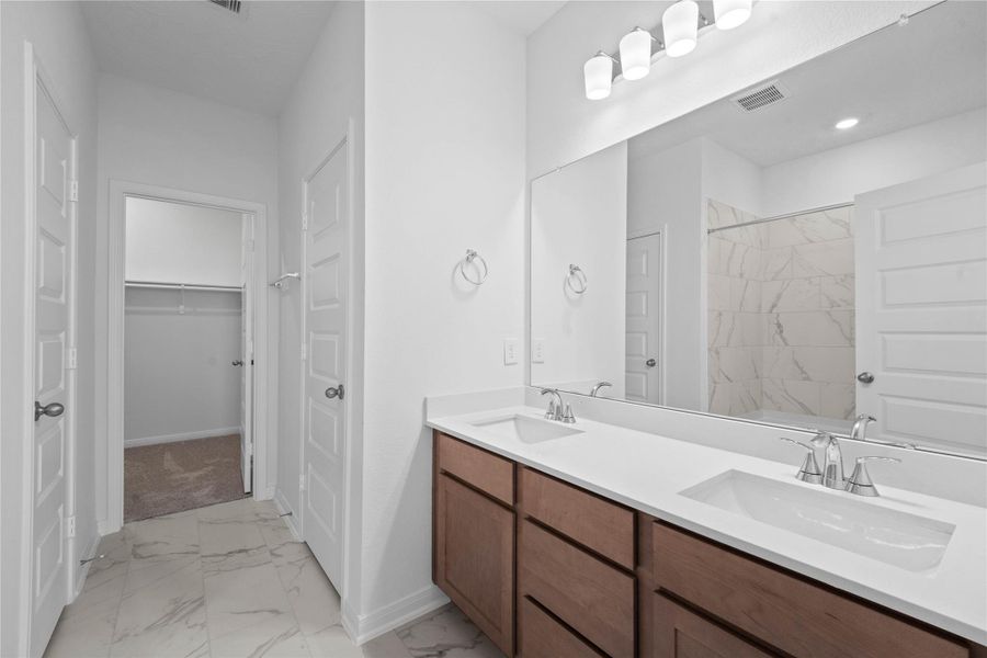 This primary bathroom is definitely move-in ready! Featuring stained cabinets with light countertops, dual vanities, high ceilings, neutral paint, walk-in closet, sleek and modern finishes.