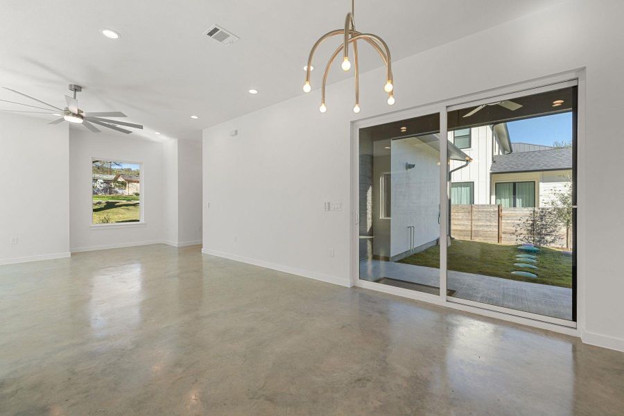 Unfurnished room with visible vents, concrete floors, baseboards,chandelier