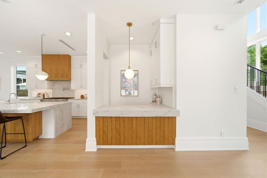 Stylish bar with quartz countertops and custom white oak cabinetry, perfectly positioned for entertaining. Stylish bar with quartz countertops and custom white oak cabinetry, perfectly positioned for entertaining.