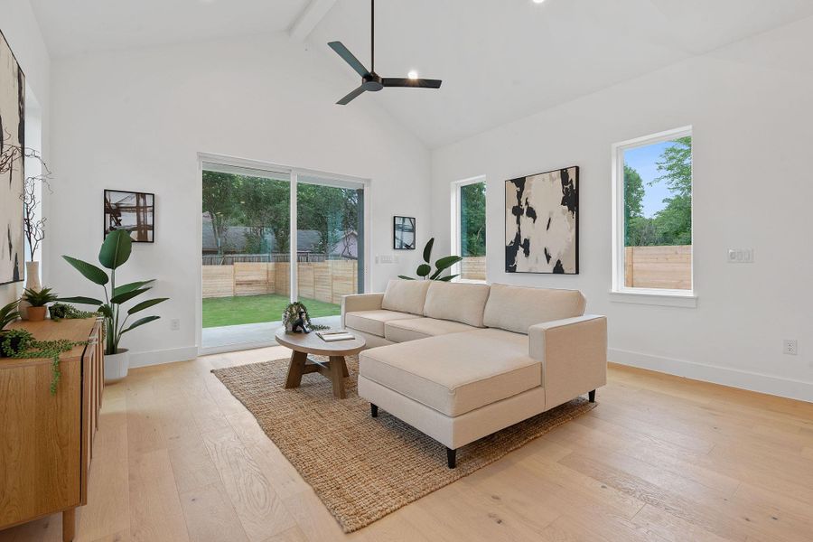 Living area featuring beamed ceiling, light wood-type flooring, plenty of natural light, high vaulted ceiling, and a ceiling fan Living area featuring beamed ceiling, light wood-type flooring, plenty of natural light, high vaulted ceiling, and a ceiling fan
