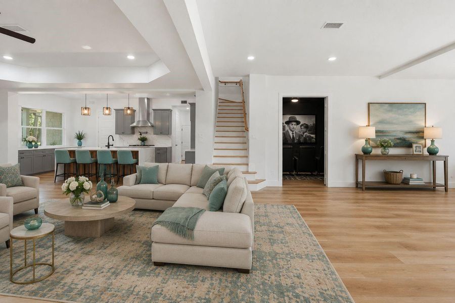 The oversized grand room has so many architectural details. Beside the stairs is the media/movie room, wide plank flooring, abundant natural lighting, open concept kitchen, tray ceilings, pendant lighting, painted bright neutral white. The oversized grand room has so many architectural details. Beside the stairs is the media/movie room, wide plank flooring, abundant natural lighting, open concept kitchen, tray ceilings, pendant lighting, painted bright neutral white.
