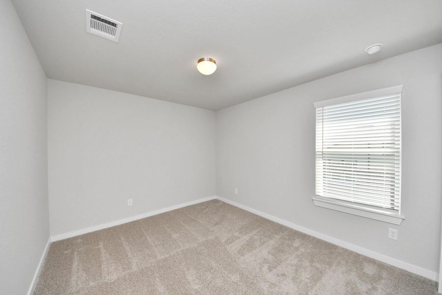 Secondary bedroom features plush carpeting, large windows that let in plenty of natural light, bright paint, and spacious closets. Sample photo of completed home with similar floor plan. Actual colors and selections may vary.