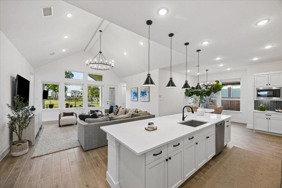 Oversized island anchors the kitchen with quartz countertops, matte black hardware, and pendant lighting, all overlooking the main living space. Bright, open layout is elevated by vaulted ceilings and a full wall of windows capturing backyard and greenbelt views. Oversized island anchors the kitchen with quartz countertops, matte black hardware, and pendant lighting, all overlooking the main living space. Bright, open layout is elevated by vaulted ceilings and a full wall of windows capturing backyard and greenbelt views.