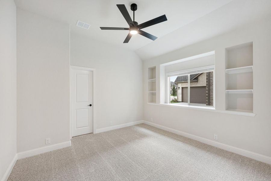 Empty bedroom with vaulted ceiling, black ceiling fan, built-in shelves, and carpet flooring Empty bedroom with vaulted ceiling, black ceiling fan, built-in shelves, and carpet flooring
