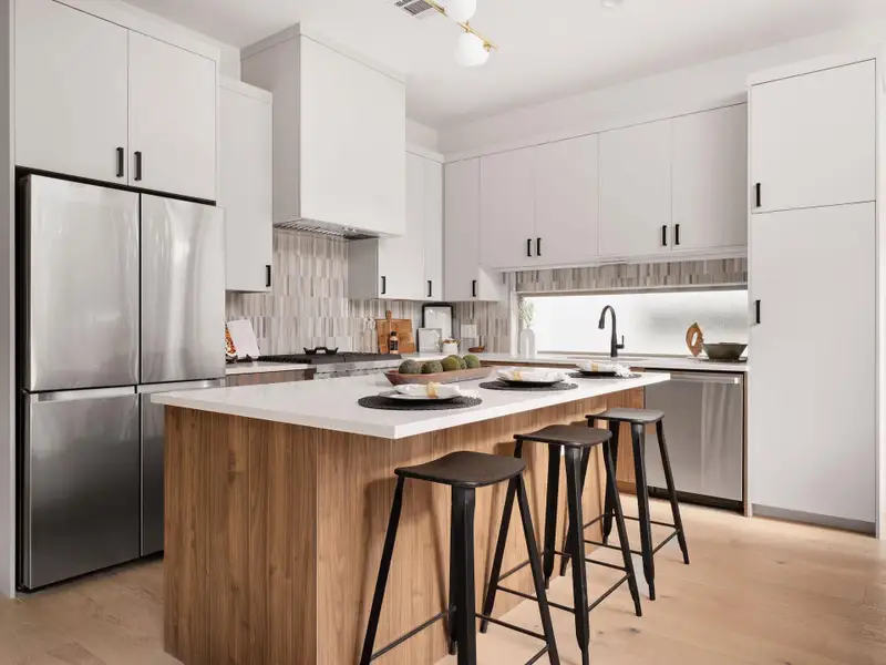 Kitchen featuring appliances with stainless steel finishes, backsplash, white cabinets, light wood-type flooring, and a breakfast bar