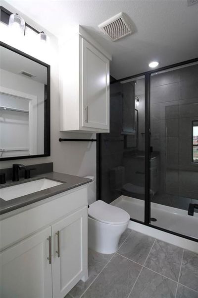 Bathroom with vanity, toilet, and a shower with shower door