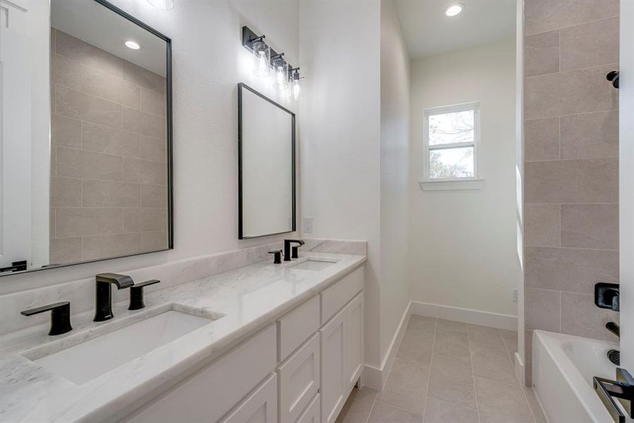 Bathroom featuring tile patterned floors, vanity, and tiled shower / bath