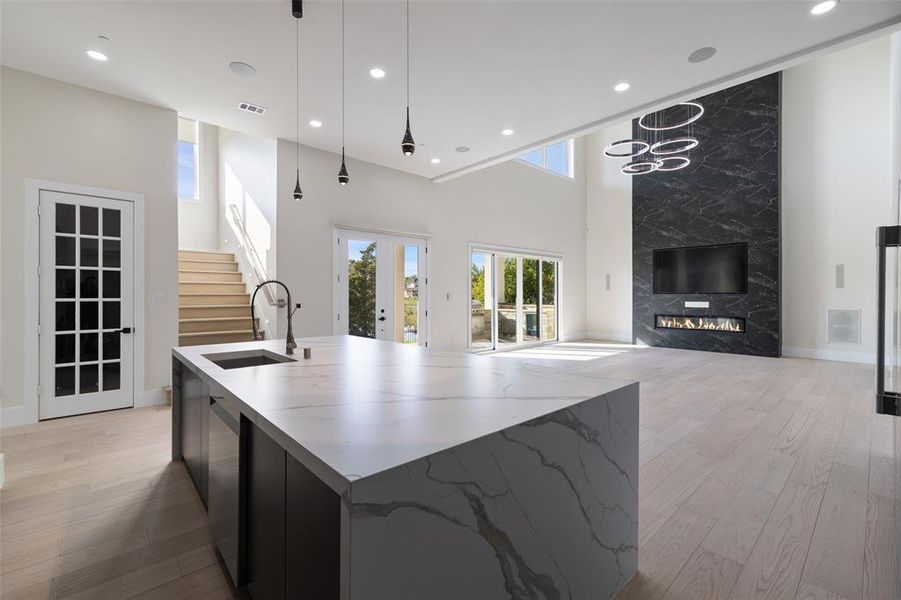 Kitchen featuring light hardwood / wood-style flooring, hanging light fixtures, an island with sink, and sink