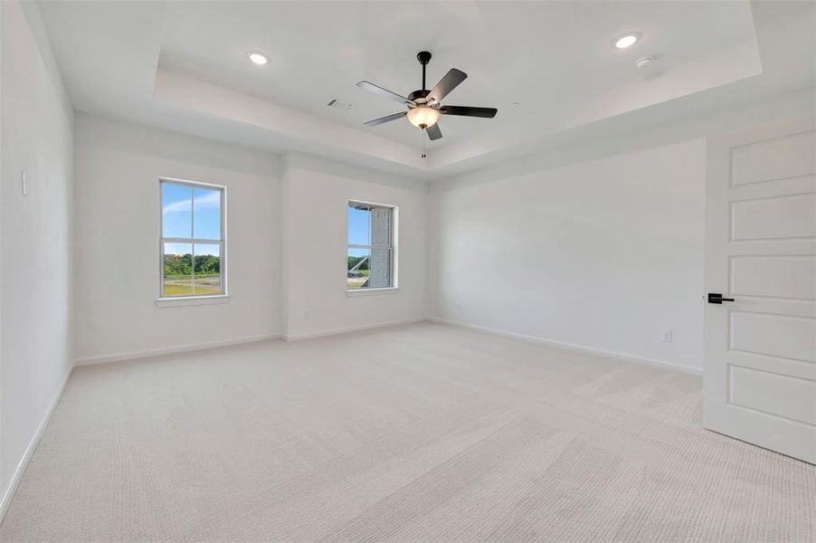 Spacious room featuring a tray ceiling, recessed lighting, and a contemporary ceiling fan Spacious room featuring a tray ceiling, recessed lighting, and a contemporary ceiling fan