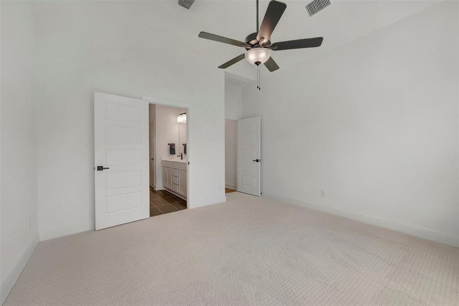 Spacious room featuring light-colored carpeting, a ceiling fan with integrated lighting, and a white interior door with black hardware
