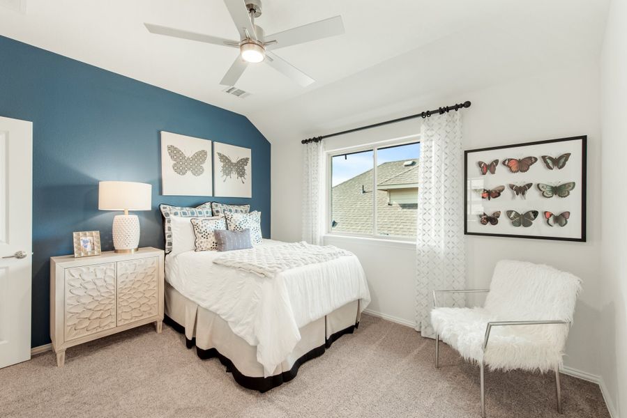 Bedroom with blue accent wall, ceiling fan, carpet flooring, and a window with white curtains