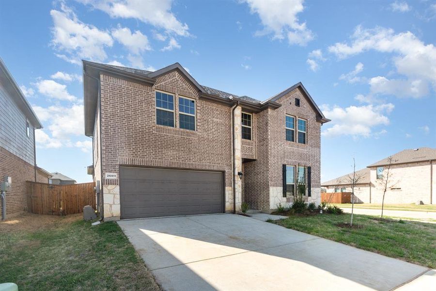 Traditional home with concrete driveway, fence, an attached garage, a front yard, and brick siding
