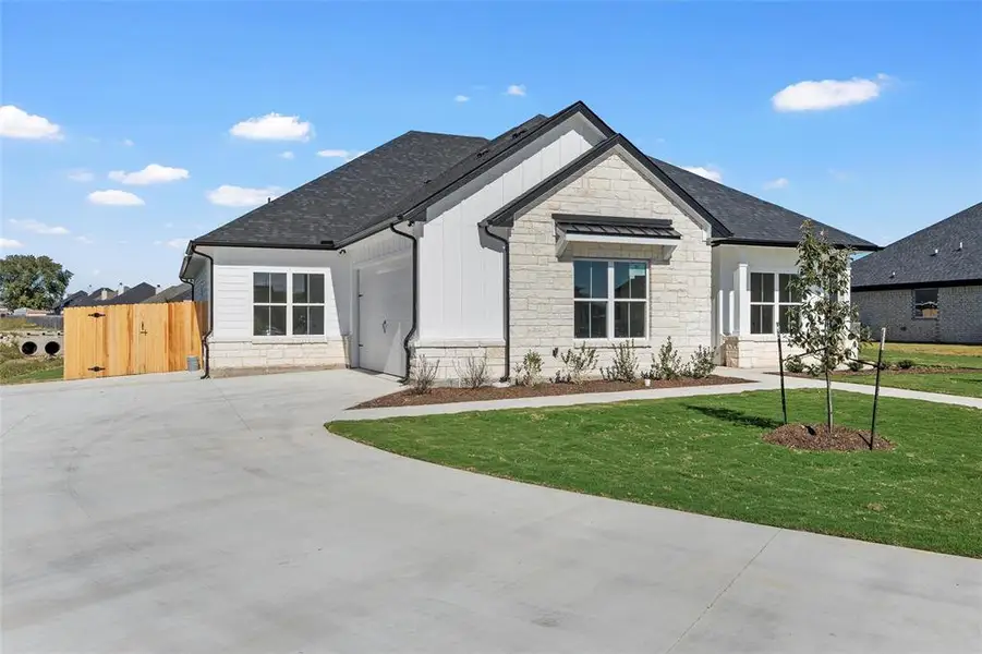 Modern farmhouse with stone siding, driveway, a garage, a shingled roof, and board and batten siding
