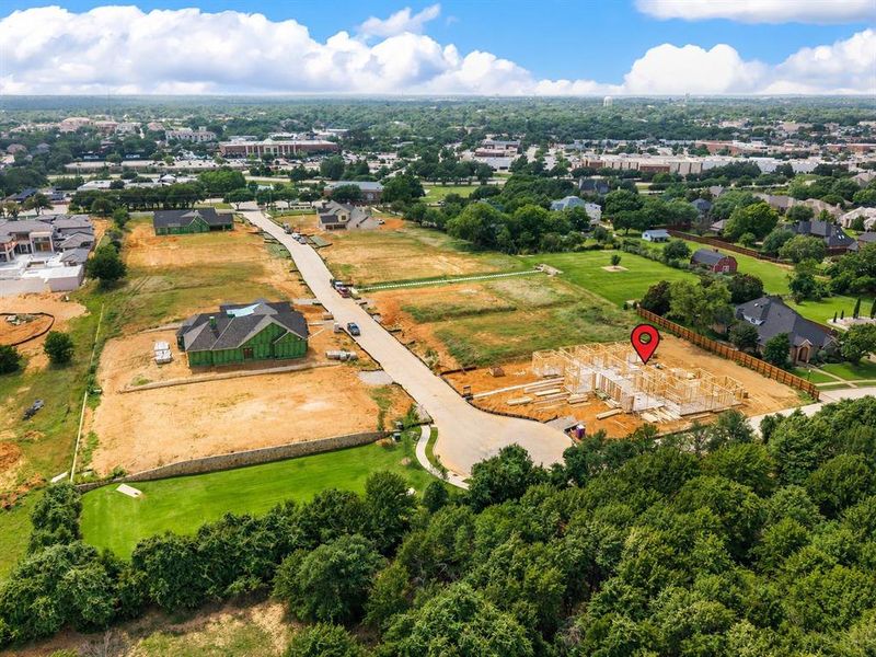 New construction opportunity featuring a framed structure, surrounding undeveloped land, a paved street, and established perimeter trees
