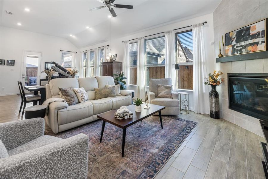 Living room with a tile fireplace, healthy amount of natural light, wood finish floors, recessed lighting, and lofted ceiling Living room with a tile fireplace, healthy amount of natural light, wood finish floors, recessed lighting, and lofted ceiling