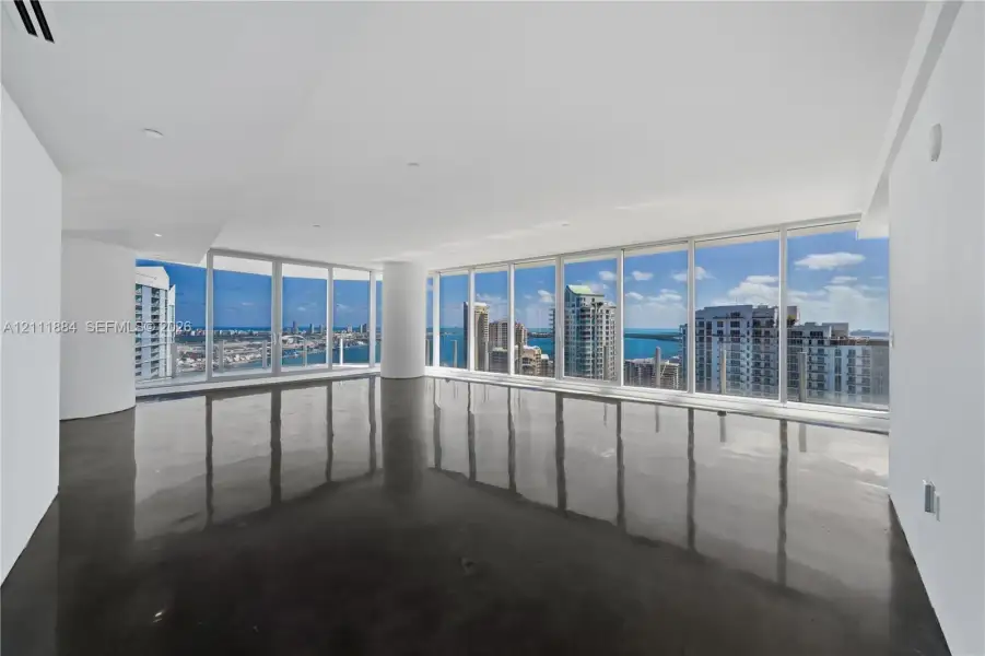Open-concept interior featuring floor-to-ceiling windows, polished concrete flooring, recessed lighting, and expansive city and water exposure Open-concept interior featuring floor-to-ceiling windows, polished concrete flooring, recessed lighting, and expansive city and water exposure
