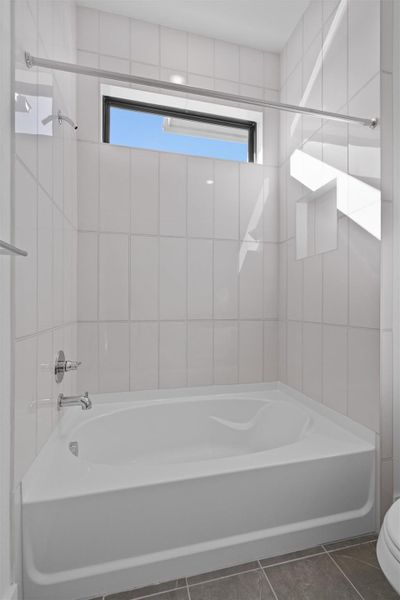 Full bathroom featuring tub / shower combination and dark tile patterned flooring Full bathroom featuring tub / shower combination and dark tile patterned flooring