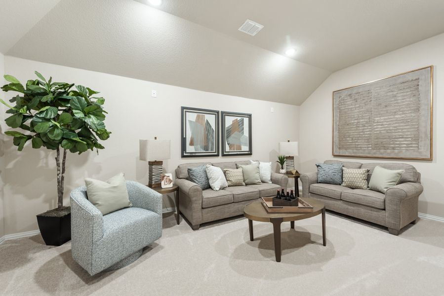 Living room with vaulted ceiling, two gray sofas, blue accent chair, and round wood coffee table on carpet