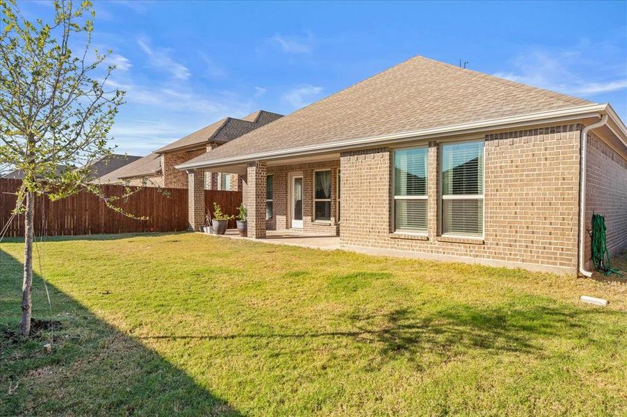 Rear view of property with a lawn and a patio