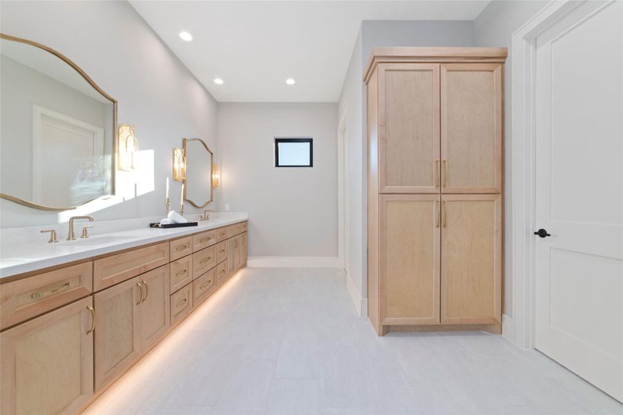 Elegant dual-sink vanity with custom cabinetry, modern fixtures, and designer lighting in the spacious primary bathroom.
