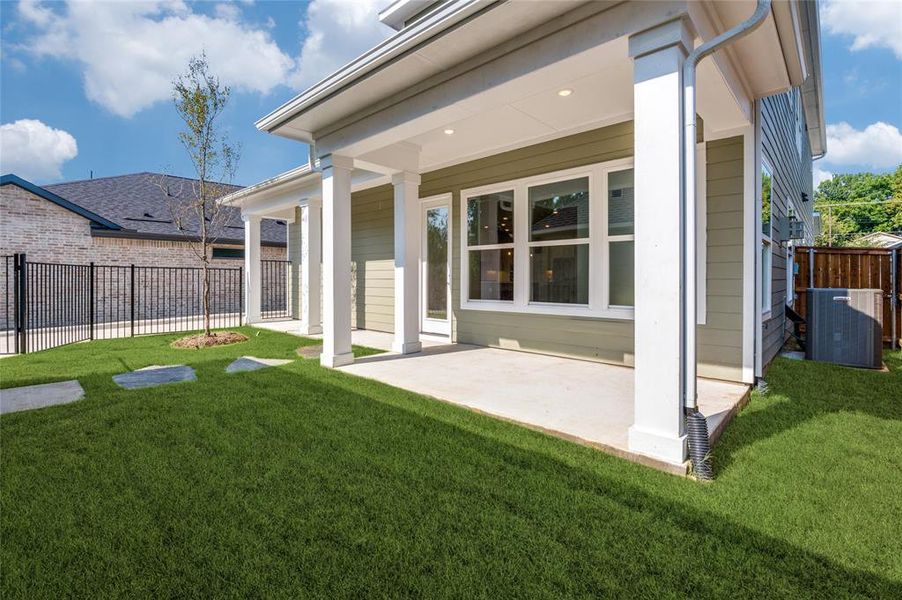 Rear view of property with central AC unit, a patio area, and a yard