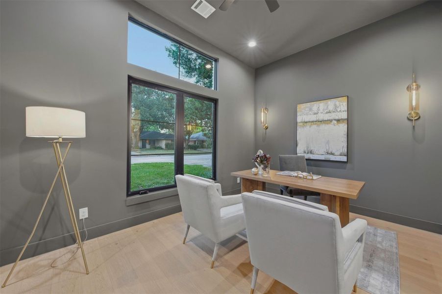 Moody, color-drenched home office in a rich cast iron hue, with front-facing windows overlooking the yard and creating a sophisticated, private workspace.