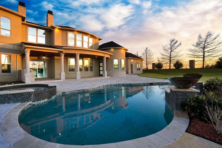 Pool at dusk with an in ground hot tub, a lawn, and a patio area