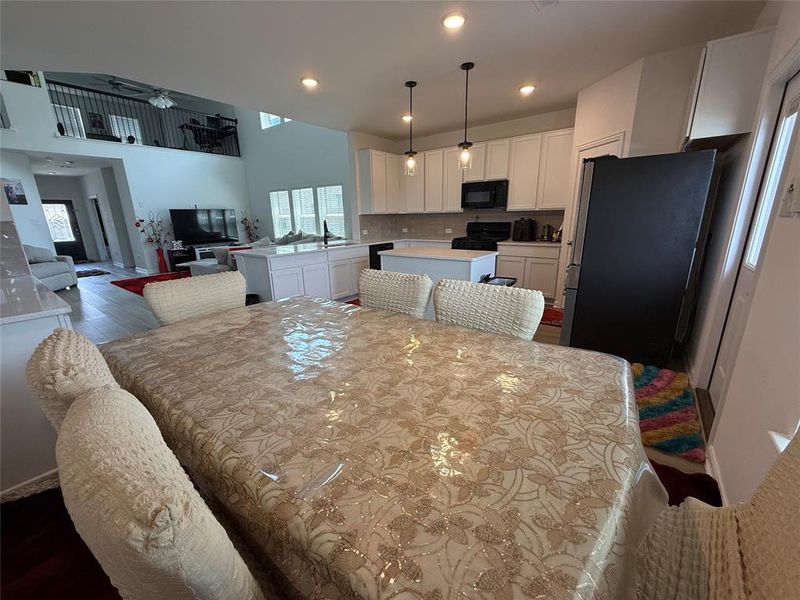 Open-concept living space featuring a modern kitchen with white cabinetry, a black range, and an island with a sink