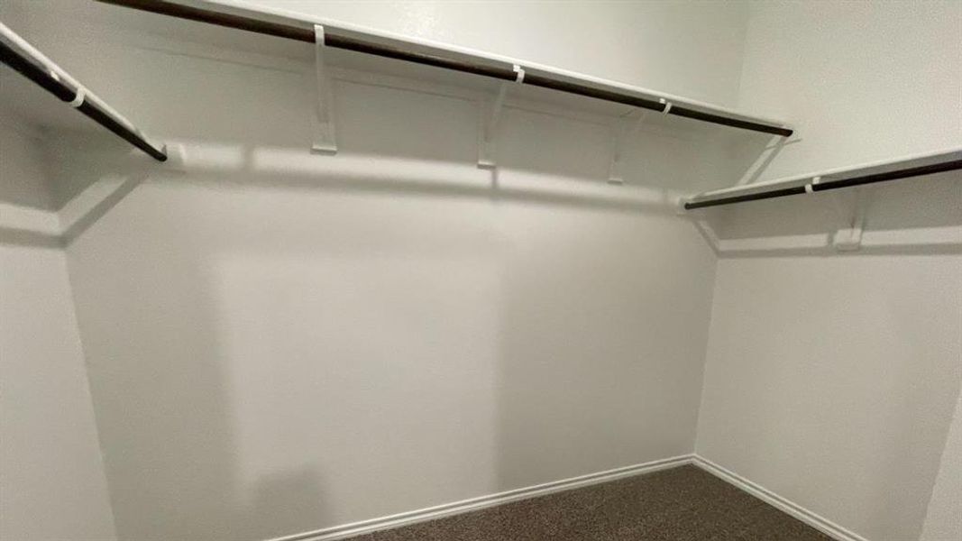 Walk-in closet featuring white painted walls and shelving with integrated hanging rods Walk-in closet featuring white painted walls and shelving with integrated hanging rods