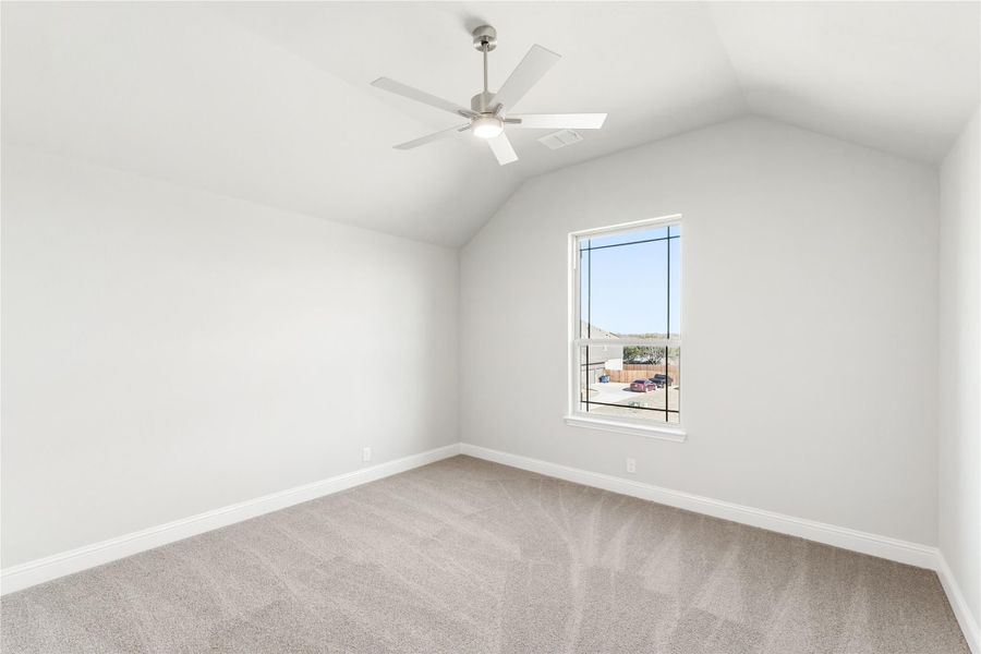 Empty bedroom with vaulted ceiling, ceiling fan, carpet flooring, and single window Empty bedroom with vaulted ceiling, ceiling fan, carpet flooring, and single window