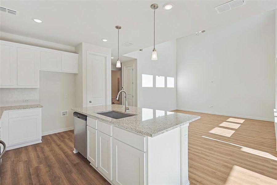 Kitchen with white cabinetry, a kitchen island with sink, light stone countertops, and dark wood-style flooring