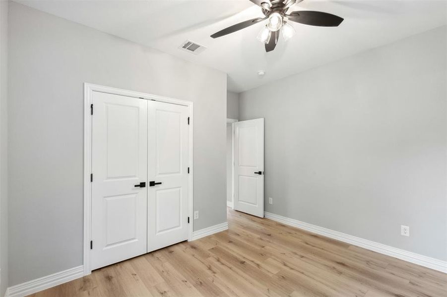 Kitchen with a center island, light wood-type flooring, appliances with stainless steel finishes, white cabinetry, and ceiling fan