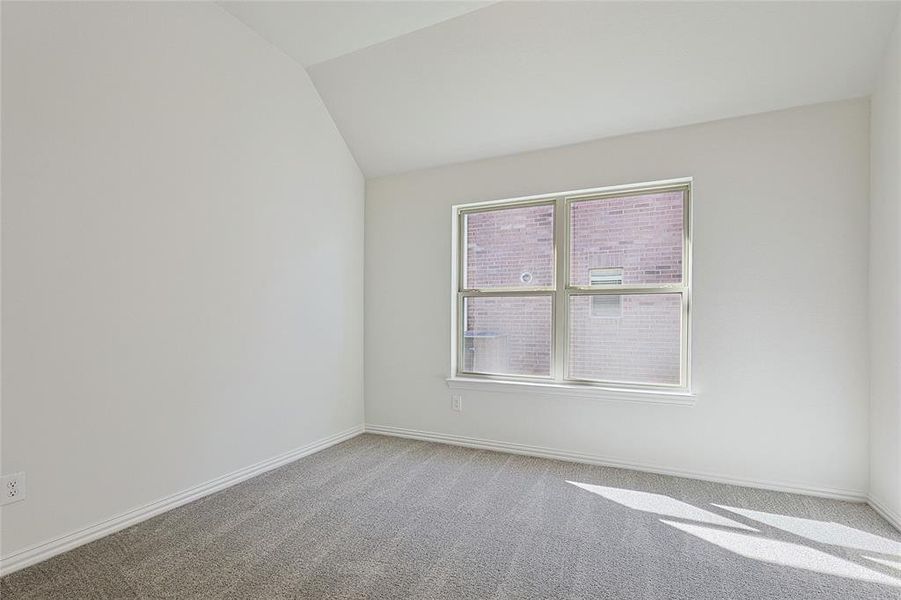 Carpeted empty room featuring vaulted ceiling