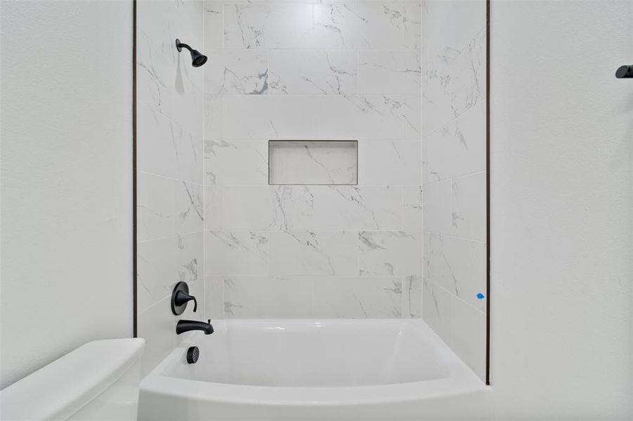 Bathroom featuring tiled shower / bath combo and toilet