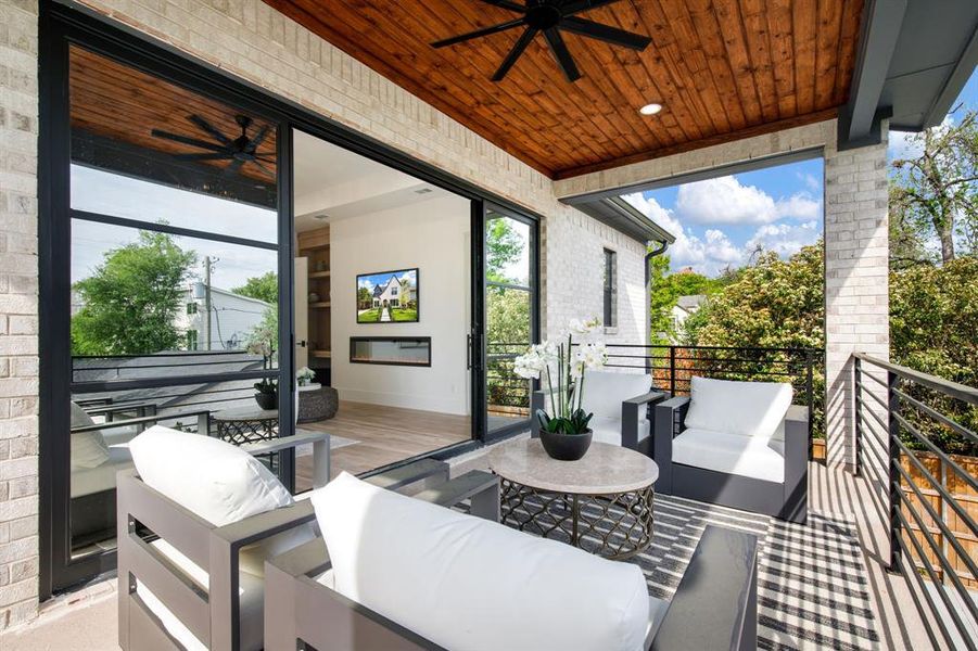 Covered outdoor balcony featuring a wood plank ceiling with recessed lighting and ceiling fan, light-colored brick exterior, and metal railing Covered outdoor balcony featuring a wood plank ceiling with recessed lighting and ceiling fan, light-colored brick exterior, and metal railing