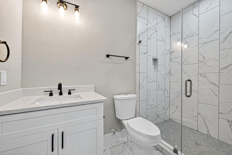 Modern refinement defines the bath, where sleek fixtures and a glass-enclosed shower transform routine into ritual.